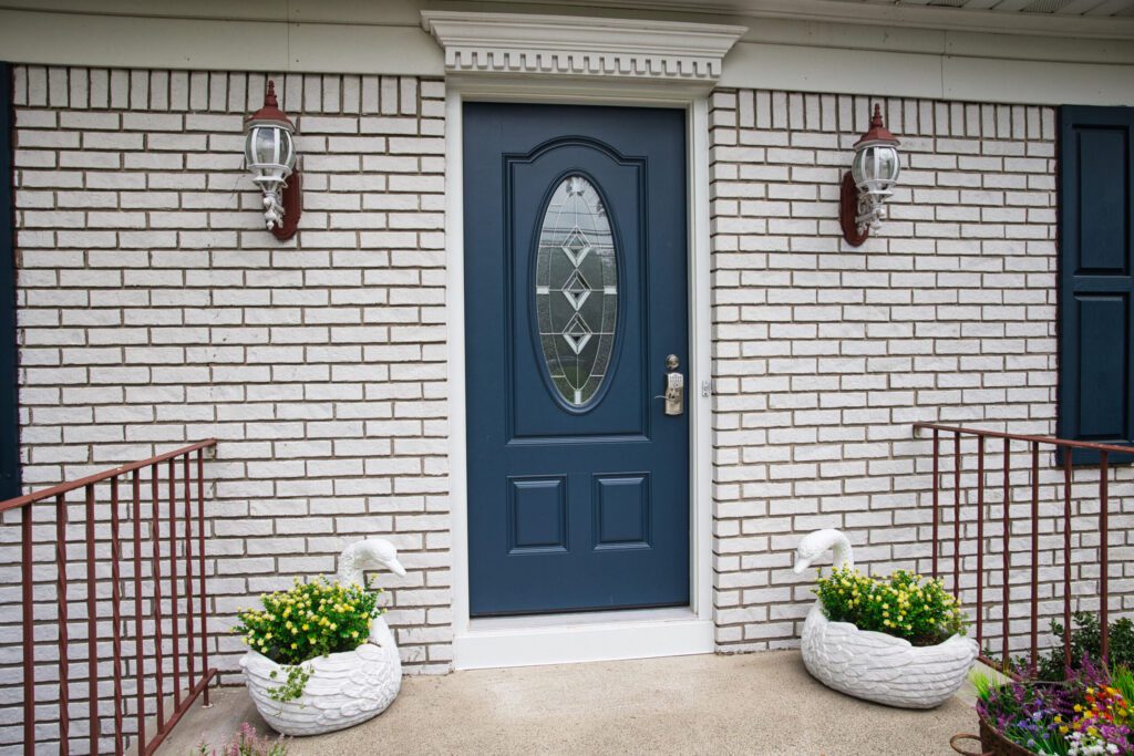 A blue front door with potted plants on the steps.