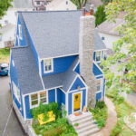 An aerial view of a blue house in a neighborhood.