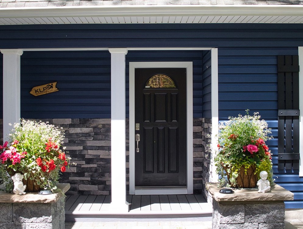 A blue house with a black door and flower pots.