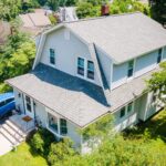 An aerial view of a house with a blue car parked in front of it.