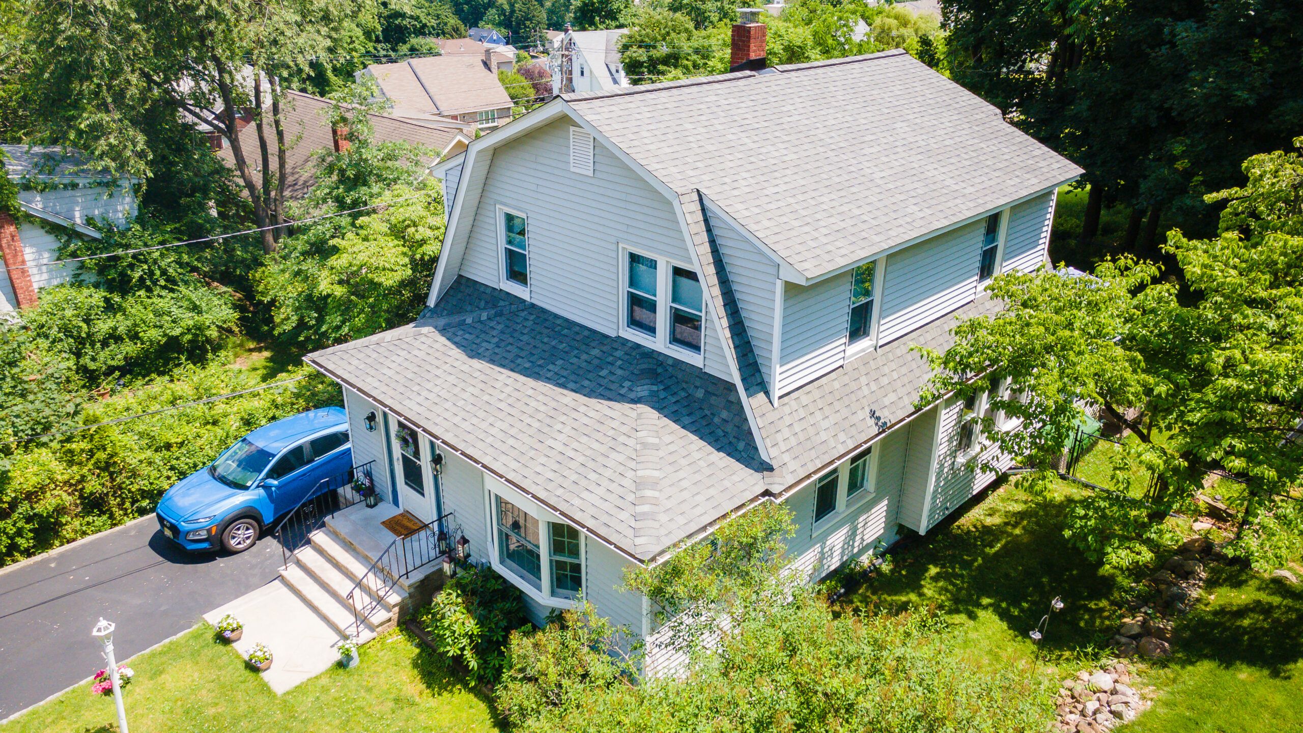 An aerial view of a house with a blue car parked in front of it.