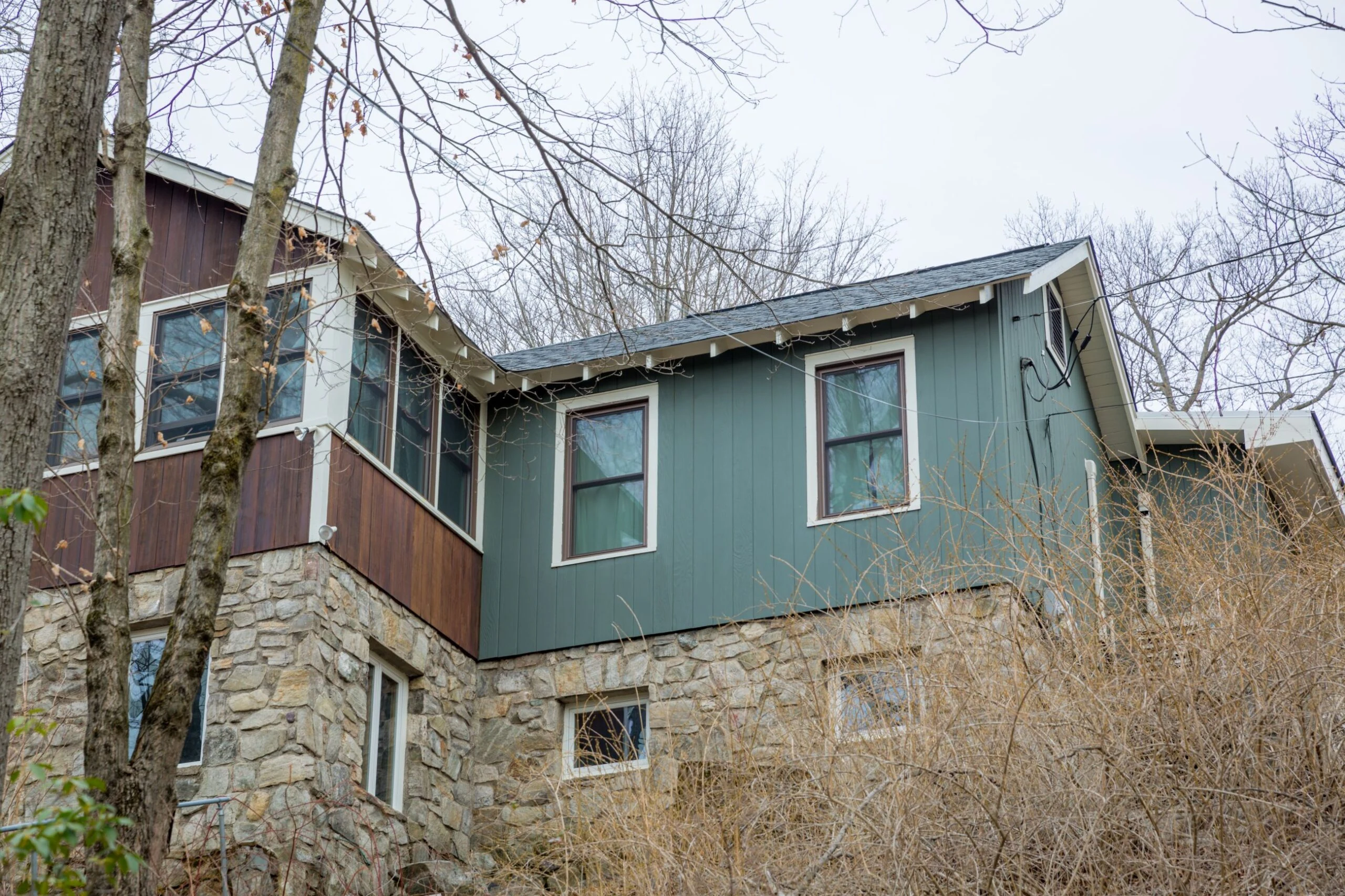 A house in the woods with green and blue siding.