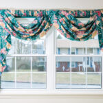 A window with a floral valance hanging in front of it.