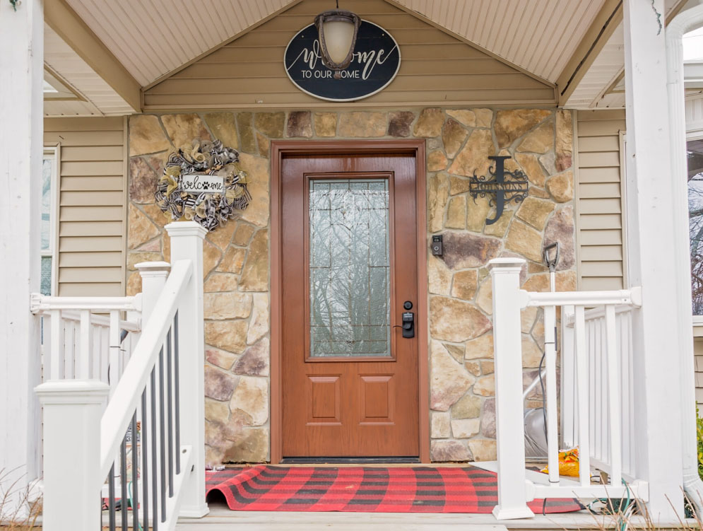The front door of a home with a plaid rug.