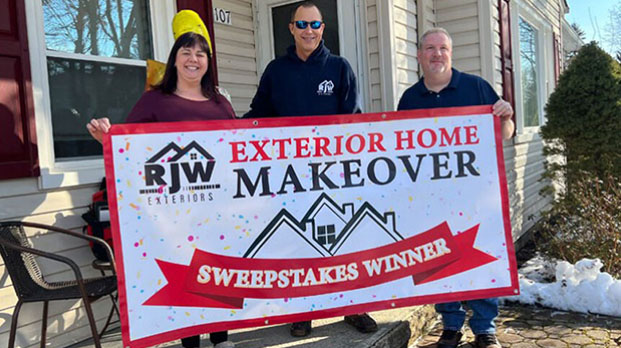 Three people holding a sign that says exterior home makeover sweepstakes winner.