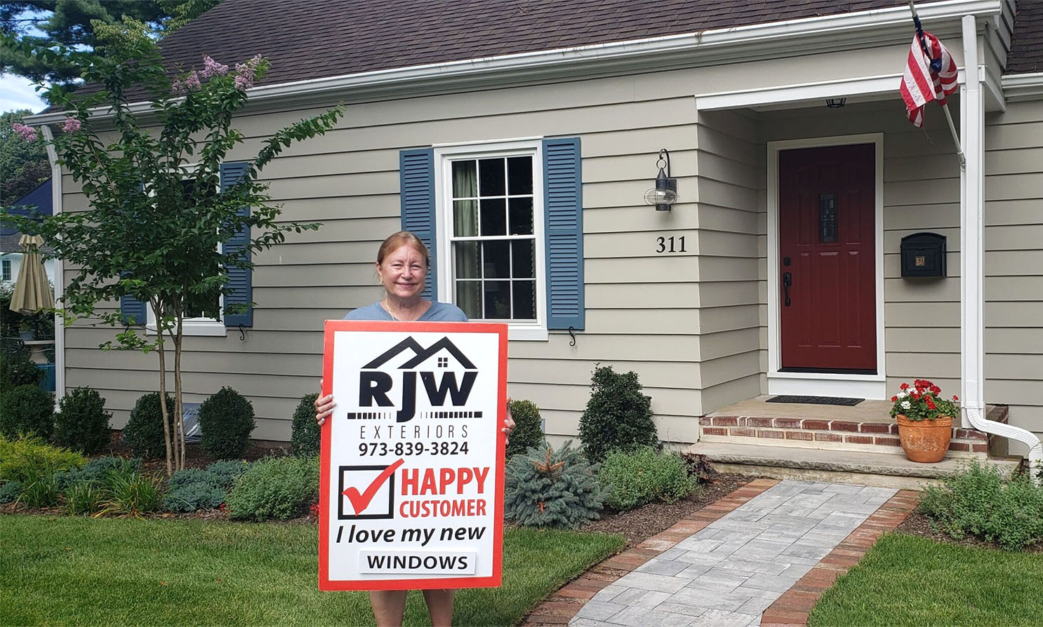 A woman holding a sign in front of a house.
