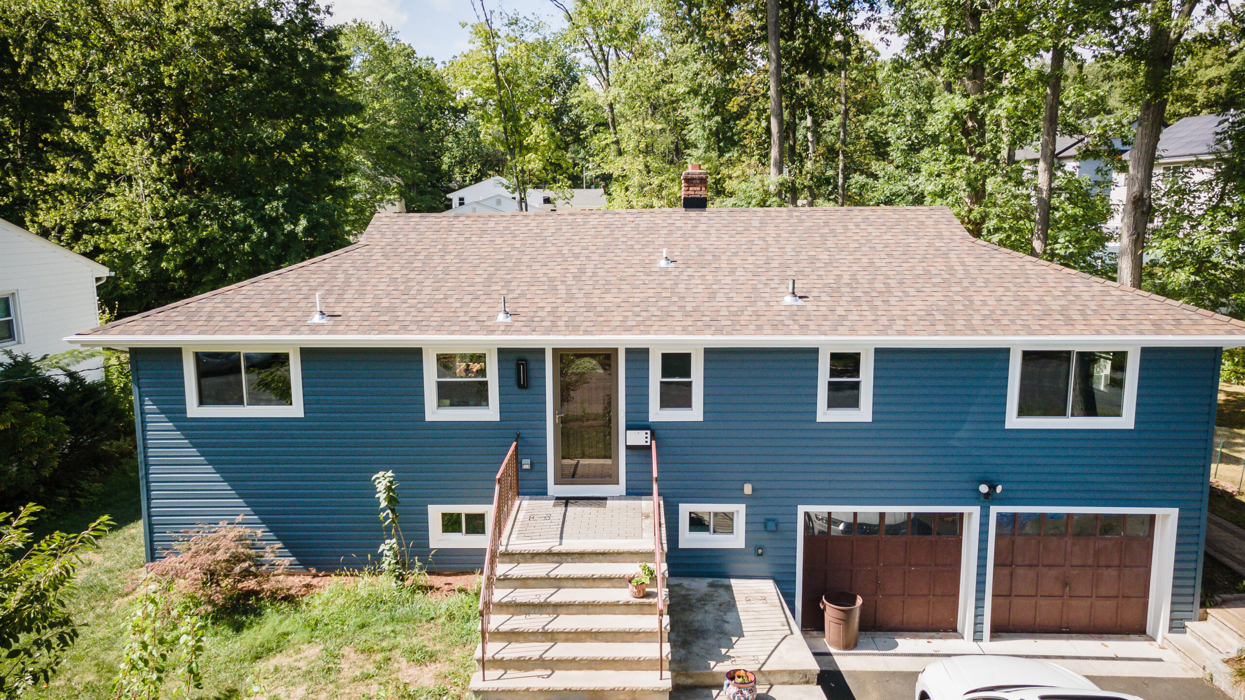 An aerial view of a blue house with a garage.