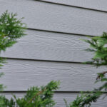 A gray siding with a tree in the background.