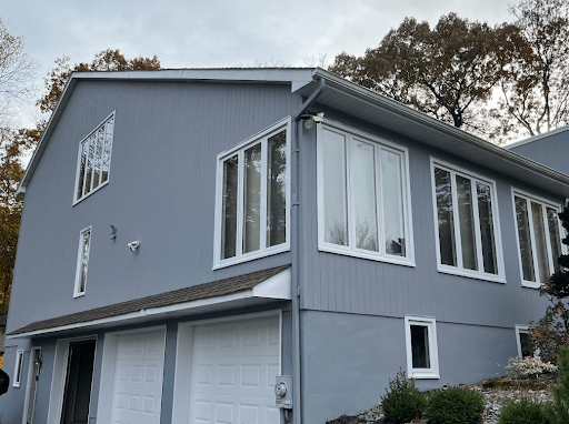 Modern home with sleek, gray siding featuring large, energy-efficient replacement windows, emphasizing their contribution to the lifespan and modernization of the house's exterior.