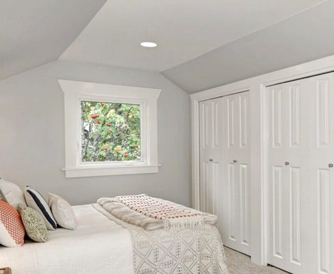A bedroom with a bed and closets.