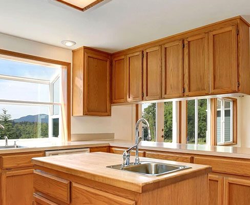 A kitchen with wood cabinets and a window.