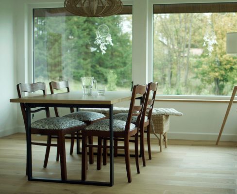 Scandinavian-inspired dining room with large windows offering a view of nature, reflecting the 2024 exterior remodeling trend of blending indoor and outdoor spaces for a serene home environment.