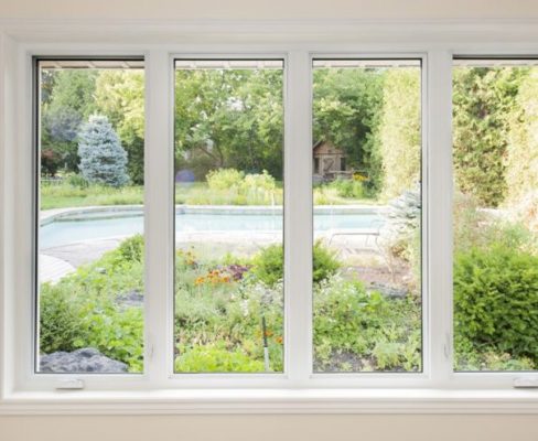 A white window with a view of a garden.